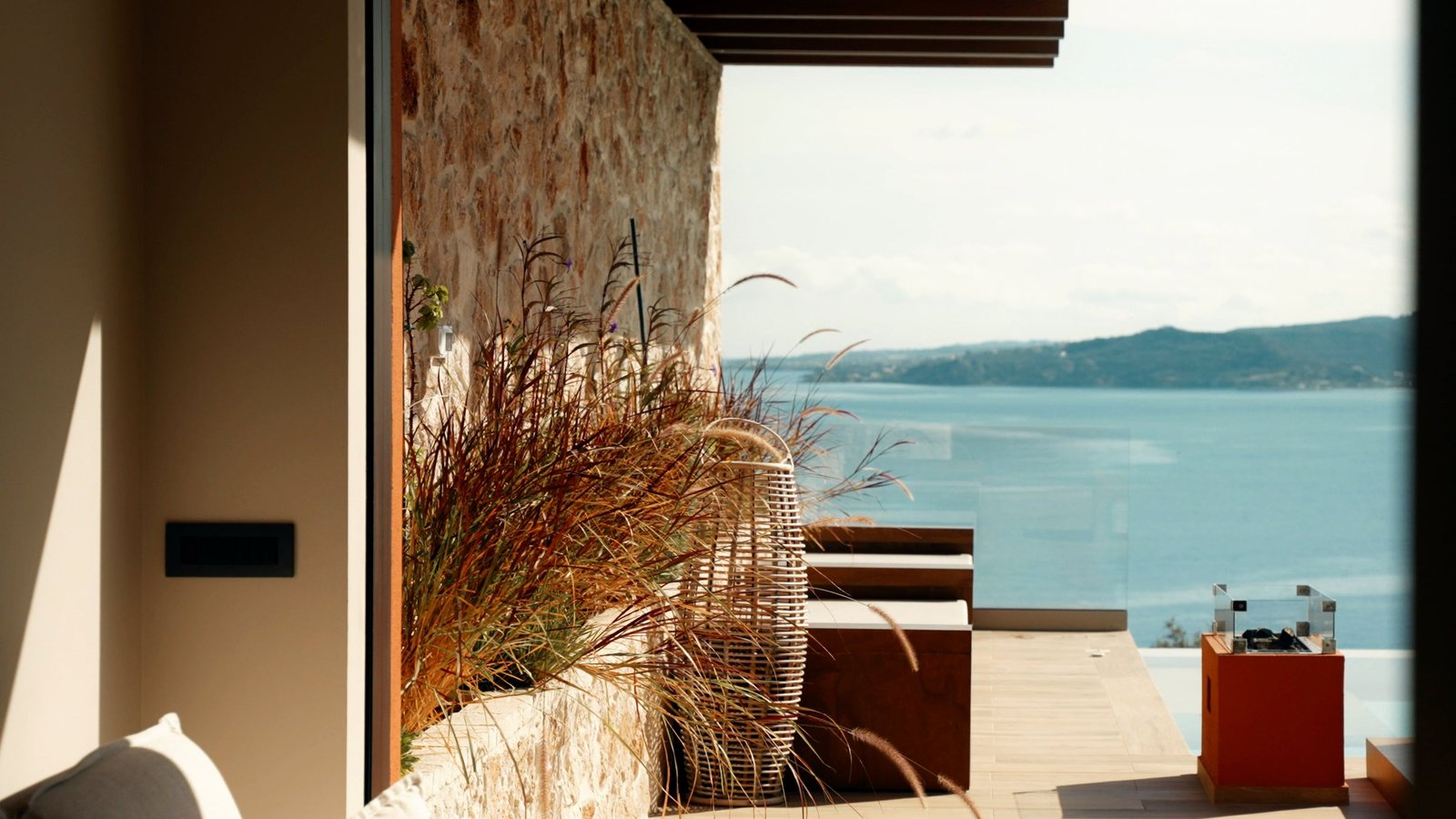 From inside a house: a stone wall, grasses, the sea beyond
