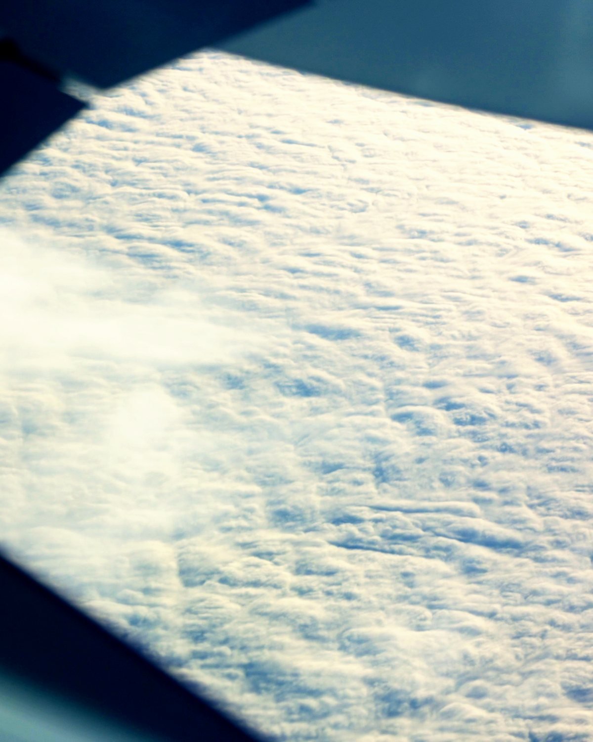 An aircraft wing above a sea of cloud in full sun